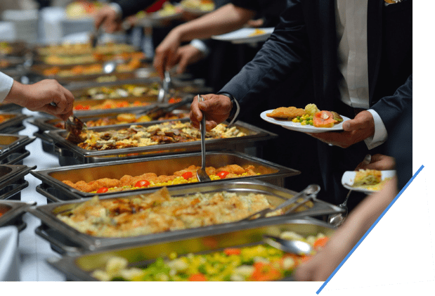 People in line getting catered food at a table.
